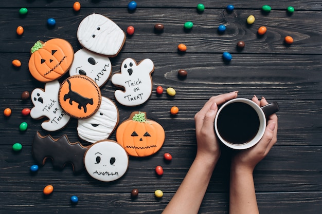 Uma xícara de café com doces de cores e pães de gengibre assustadores no Halloween.