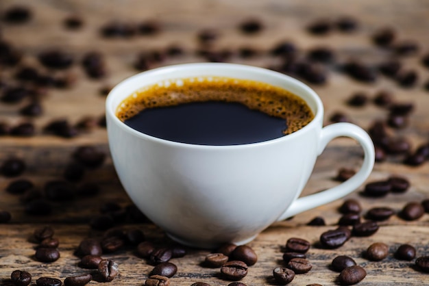 Uma xícara de café com grãos de café em fundo de madeira