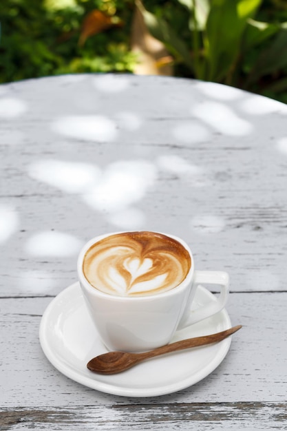 Uma xícara de café com leite na mesa de madeira branca