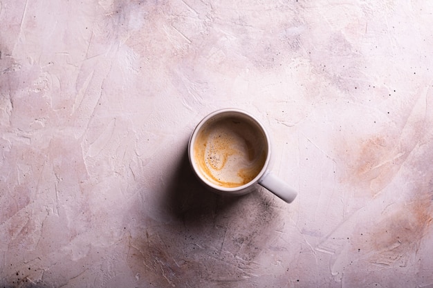 Uma xícara de café com leite plano deitado sobre um fundo de cor clara de perto