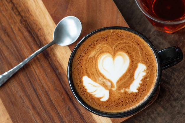 Uma xícara de café com leite quente arte em fundo de madeira