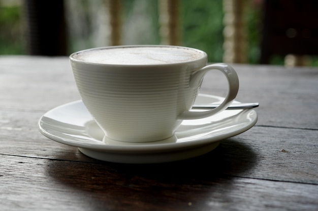 Uma xícara de café com leite quente em uma mesa de madeira