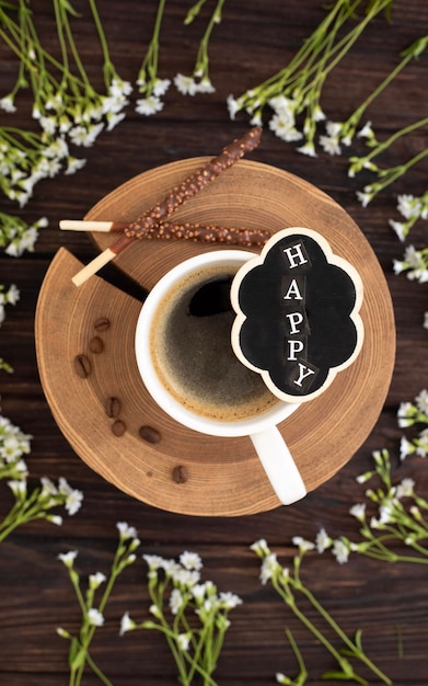 Uma xícara de café com um biscoito feliz e uma xícara de café em um pires.