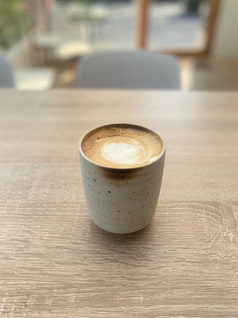 Uma xícara de café com um cappuccino espumoso em uma mesa de madeira.