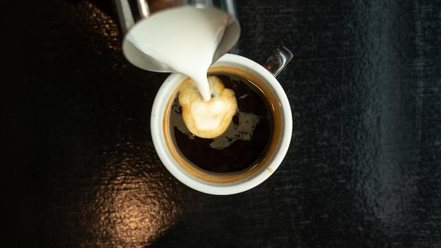 Uma xícara de café com um creme sendo derramado nela.