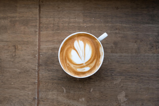 Uma xícara de café com um desenho de flor no topo.