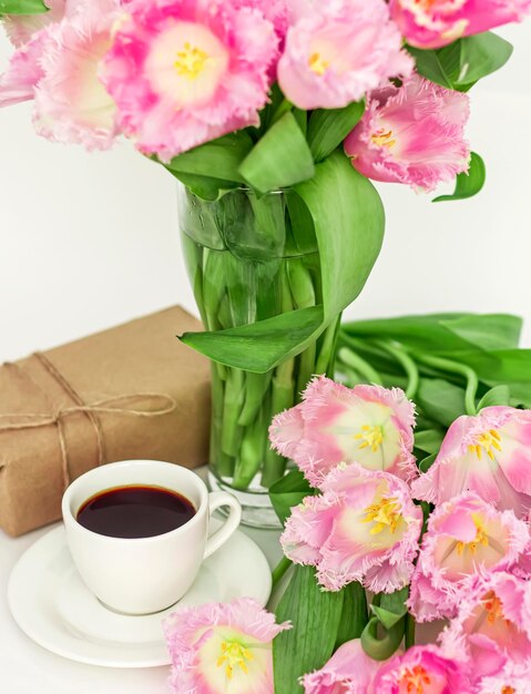 Uma xícara de café com um presente e tulipas um presente para uma mulher no dia das mães closeup