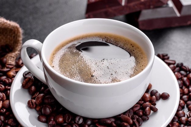 Uma xícara de café da manhã fresco e perfumado para um começo alegre do dia. Xícara de café linda com café em uma mesa escura