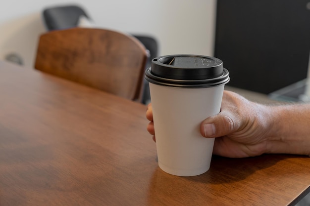Uma xícara de café de papel branco na mão. para maquete. isolado., copie o espaço