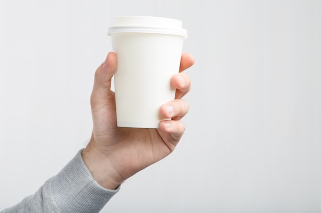 Uma xícara de café de papel na mão. Livro Branco xícara de café na mão isolada