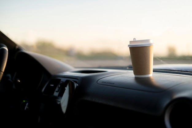 Uma xícara de café de papel para viagem dentro do carro