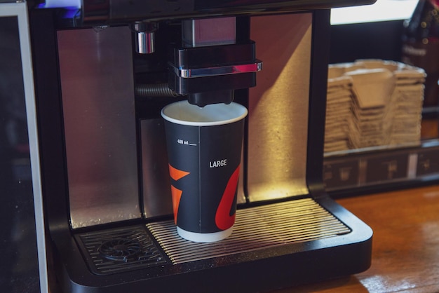 Uma xícara de café de papelão é preparada usando uma máquina de café em um posto de gasolina