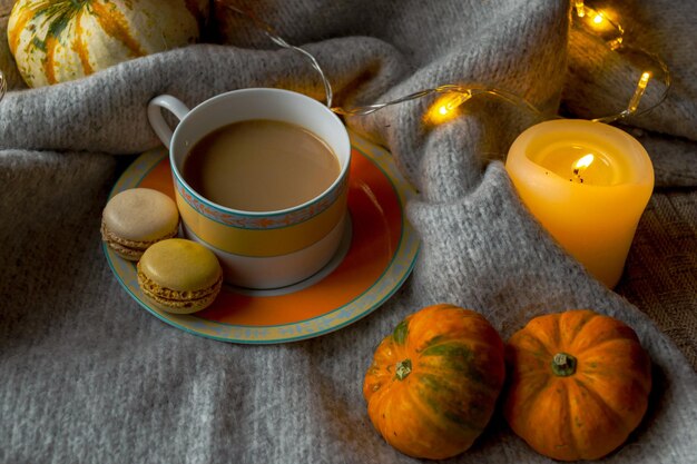 Uma xícara de café e dois biscoitos com uma manta de lã quente à luz de velas