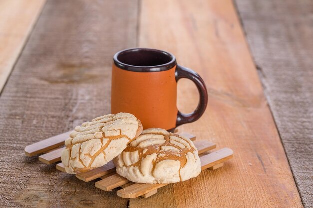 Uma xícara de café e dois pastéis em uma bandeja de madeira