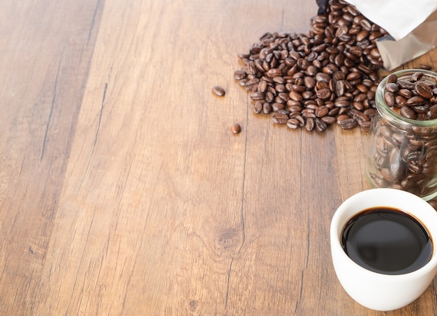 Uma xícara de café e feijão no fundo da mesa de madeira