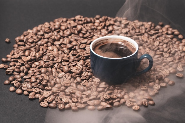 Uma xícara de café e grãos de café em um fundo preto uma bebida aromática e energética