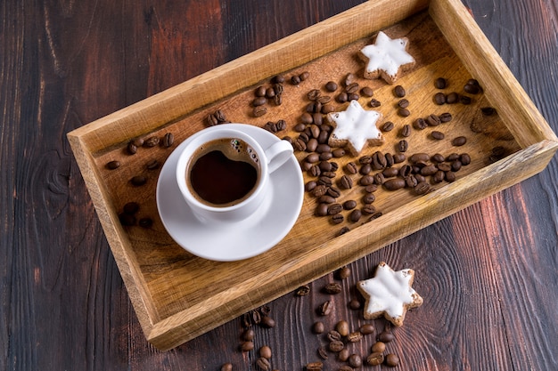 Uma xícara de café e grãos de café em uma bandeja de madeira