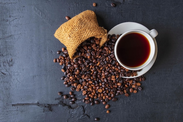 Uma xícara de café e grãos de café torrados em uma sacola marrom.