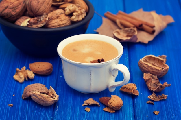 Uma xícara de café e nozes na superfície de madeira