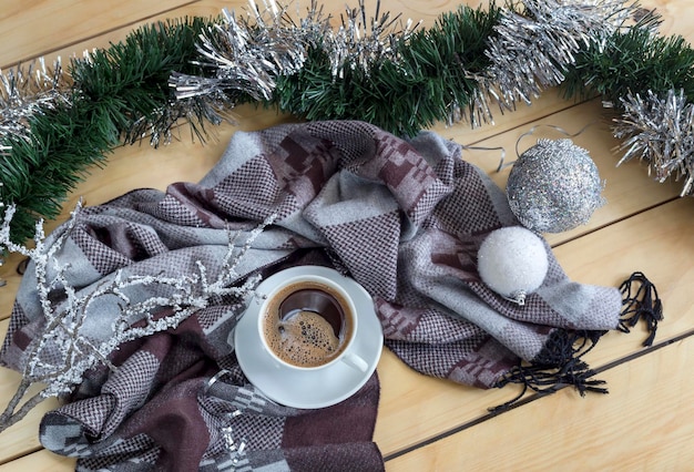 Uma xícara de café e um cachecol de inverno em uma mesa de madeira fechada