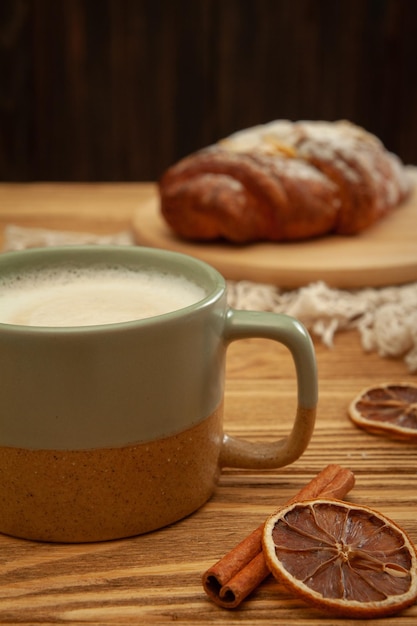 Uma xícara de café e um croissant em um fundo de madeira. doce café da manhã