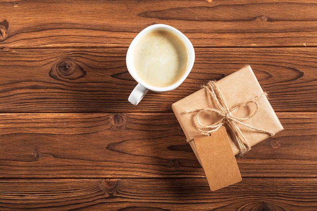 Uma xícara de café e um presente embrulhado em uma mesa de madeira