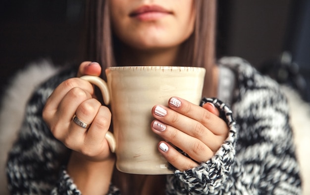 Uma xícara de café em belas mãos femininas e belos lábios