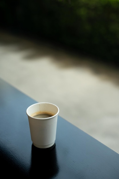 Uma xícara de café está sobre uma mesa em frente a uma janela.