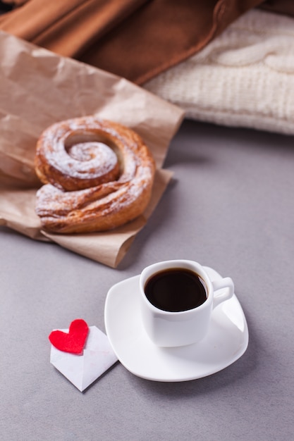 Uma xícara de café expresso em um pires e um bun em camadas