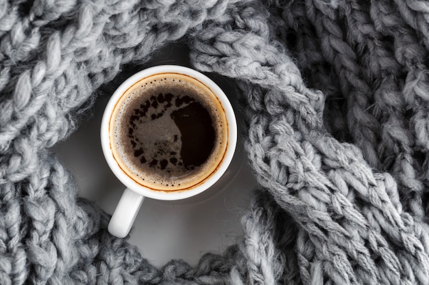 Uma xícara de café expresso, envolto em um cachecol cinza quente de lã. Vista do topo