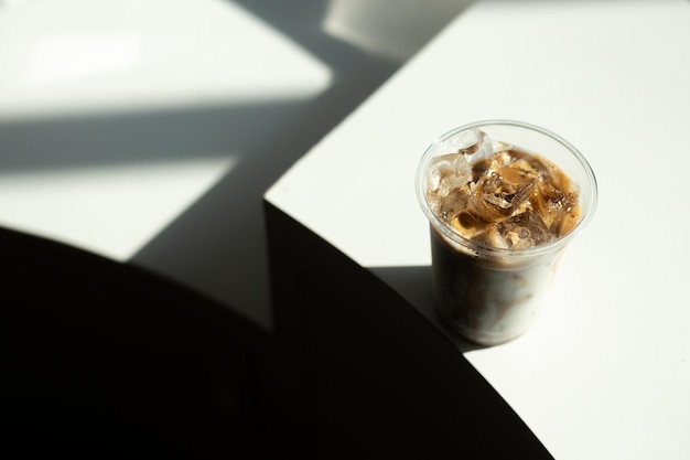 Uma xícara de café gelado está sobre uma mesa com cubos de gelo.