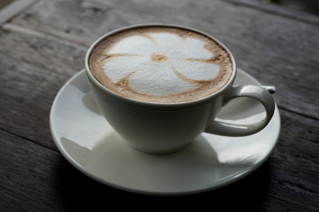 Uma xícara de café latte art quente em uma mesa de madeira