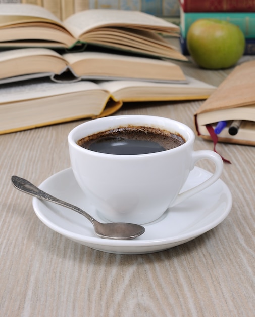Uma xícara de café na mesa no contexto de um livro aberto com um caderno
