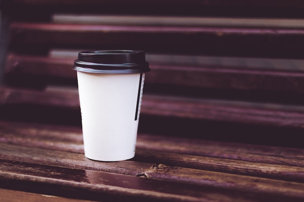 Foto uma xícara de café no banco de madeira no parque da rua