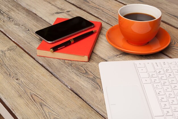Uma xícara de café no prato laranja em cima da mesa de madeira. Interior do escritório