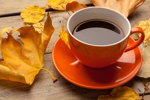 Uma xícara de café no prato laranja em cima da mesa de madeira. Interior do escritório