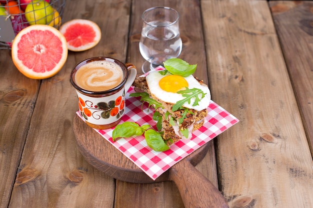 Uma xícara de café perfumado e um copo de água. Torradas com ovo e salada no café da manhã.