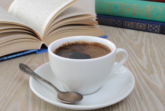 Uma xícara de café preto perfumado na mesa contra o fundo de um livro aberto