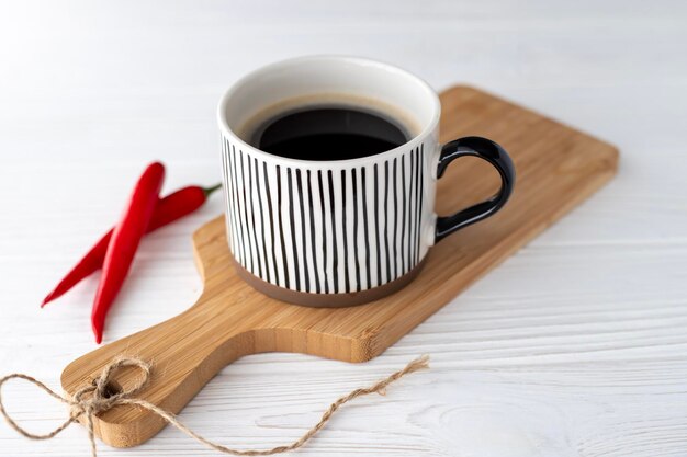 Uma xícara de café preto quente aromático sobre fundo branco e pimenta vermelha aguda
