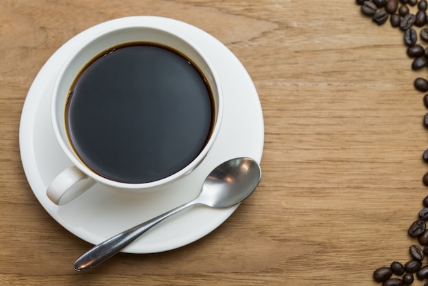 Uma xícara de café preto sobre fundo de madeira