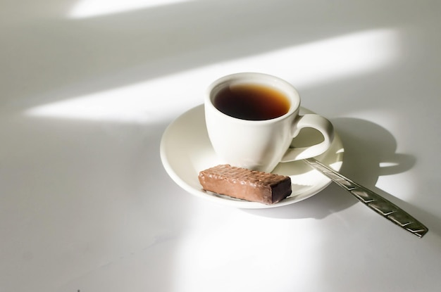 Uma xícara de café quente à luz do sol da manhã na mesa branca