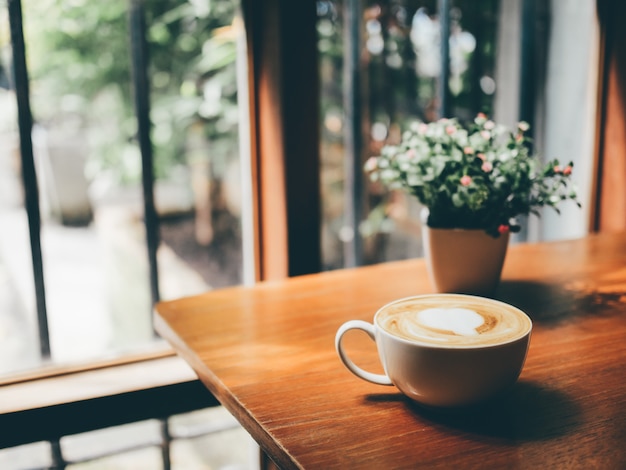 Foto uma xícara de café quente na mesa de madeira com a luz solar bonita das janelas.