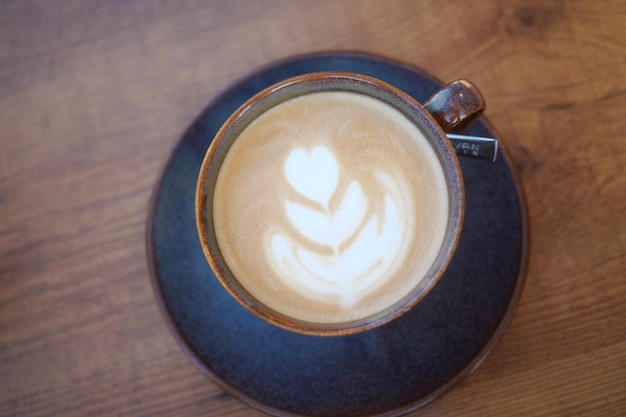 Uma xícara de café tardio com design em forma de flor na parte superior no café