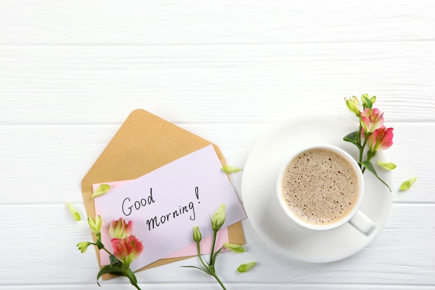 Foto uma xícara de café, um buquê de flores e um cartão com as palavras bom dia