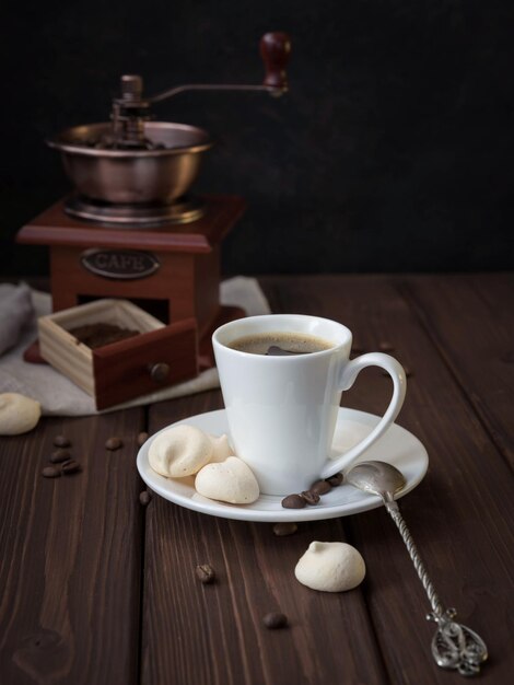 Uma xícara de café, um moedor de café e grãos de café torrados no fundo preto Espresso