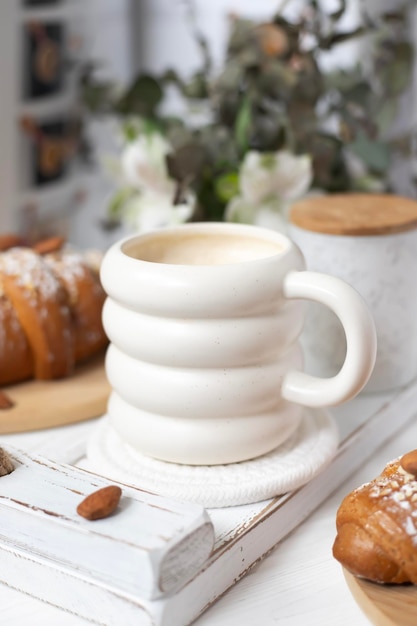 Uma xícara de cappuccino aromático e um croissant em uma bandeja branca março abril maio