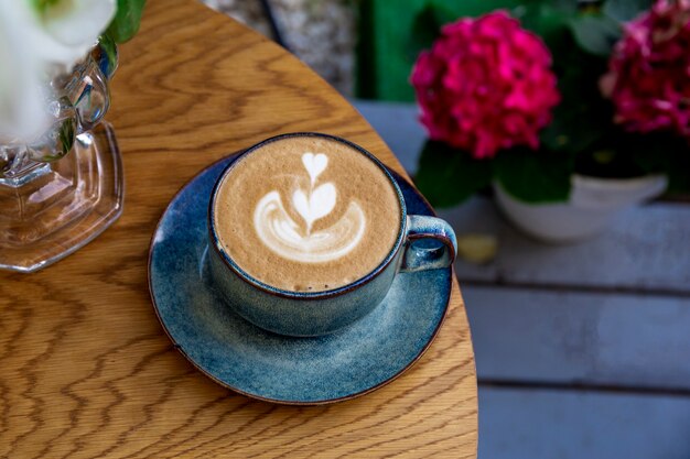 Foto uma xícara de cappuccino, café e flores sobre a mesa de um café