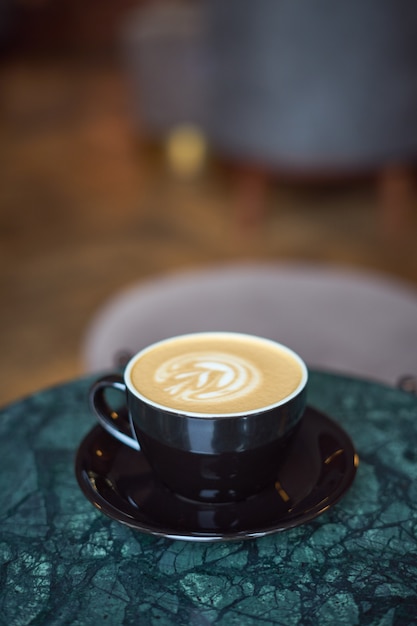 Uma xícara de cappuccino com espuma sobre uma mesa de mármore em um pequeno e acolhedor café.