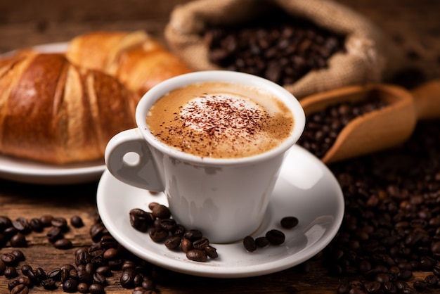 Uma xícara de cappuccino com grãos de café como plano de fundo close-up