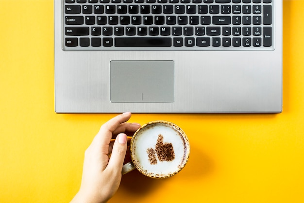 Uma xícara de cappuccino em que é desenhado um sorriso como um polegar para cima